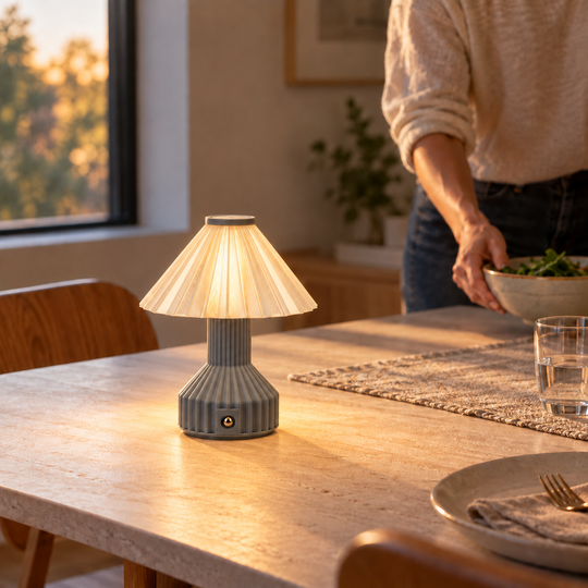 Vela table lamp glowing on a dining table as dinner is prepared.
