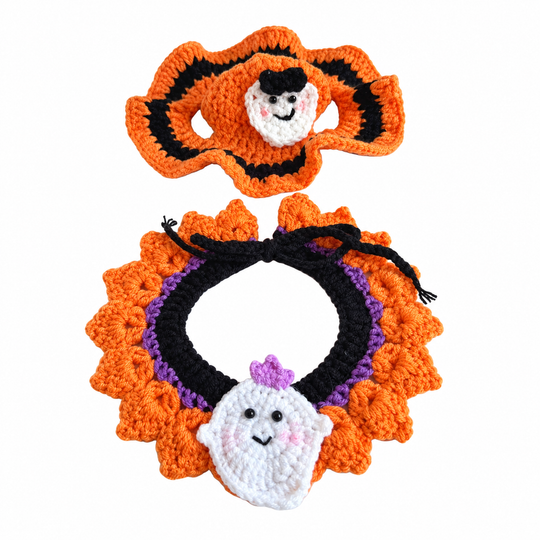 Orange crochet hat with a smiling white ghost and a black, purple and orange ruffled collar.